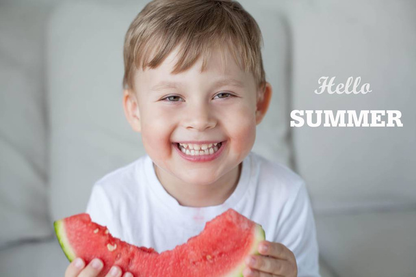 ein kleiner netter Junge von 4 Jahren isst eine Wassermelone. Sommer. Hitze. Wassermelone. Porträt eines glücklichen Jungen mit einer Wassermelone. helle Farbtöne. - Foto, Bild