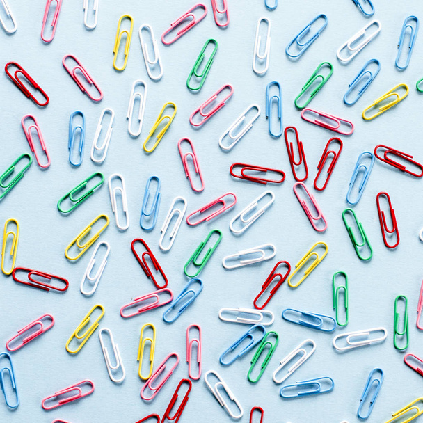 Multi-colored paper clips on blue background - Fotó, kép