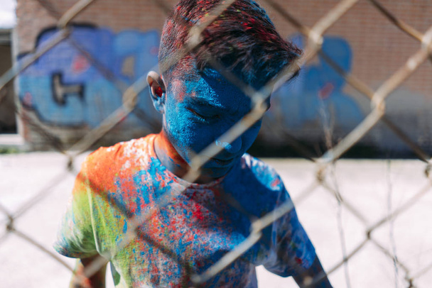 Teenager smiling behind the gate, is painted in colors - Фото, зображення