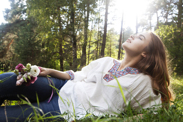 Relaxing young attractive woman in a clearing in the forest - Фото, изображение