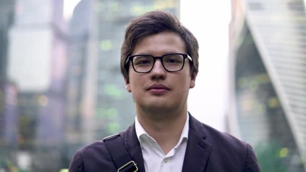 Calm young businessman portrait, smiling to the camera in a big city, summer - Video