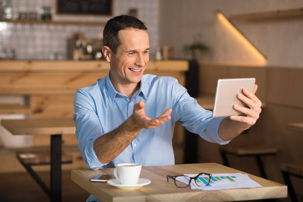 Smiling businessman using digital tablet in cafe having videochat with somebody - Foto, Bild