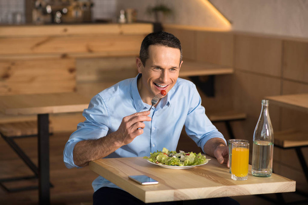 Handsome businessman having lunch in cafe eating fresh salad - Фото, изображение
