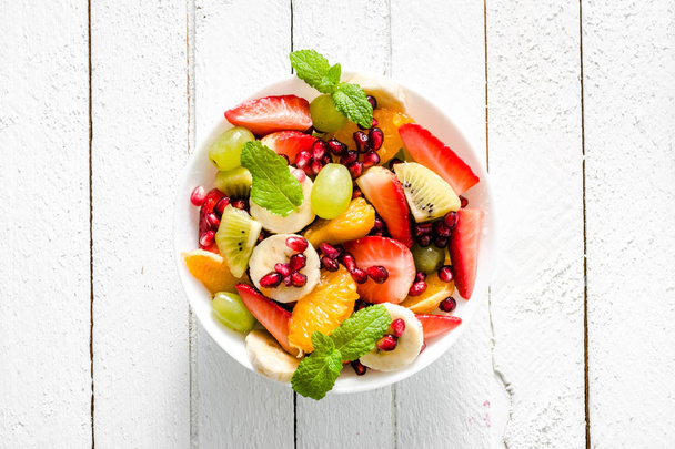 Ensalada de frutas frescas, vista superior en un tazón sobre fondo de madera, concepto de comida vegetariana - Foto, Imagen