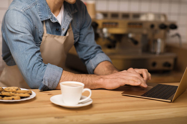 close up of cafe owner in apron using laptop - Foto, imagen