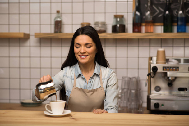 Portrait of smiling Waitress preparing espresso pouring coffee into the cup - Fotoğraf, Görsel