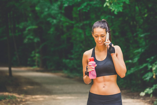 Fitness runner woman talking on smartphone in nature. - Foto, Bild