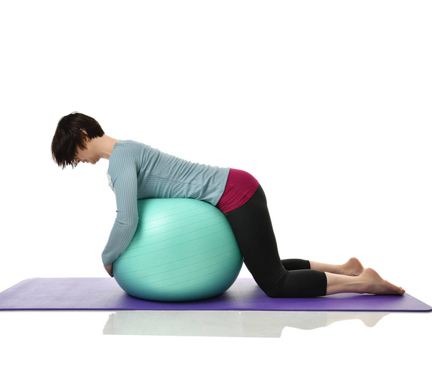Mother woman exercising doing postnatal workout. Female fitness instructor holds legs in gym and workout exercises for abdominals with green sport ball over white  - Foto, Imagen