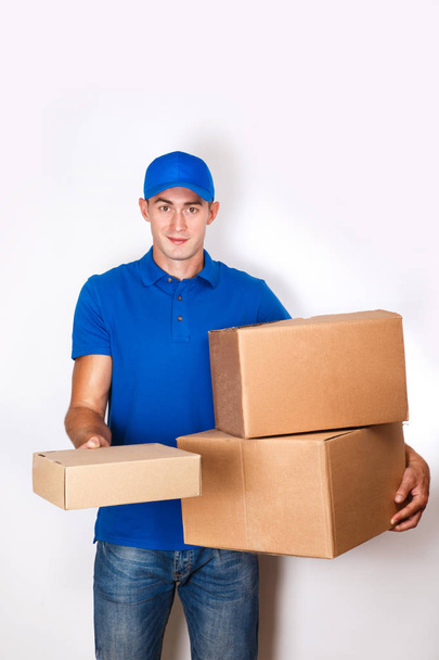 Cheerful delivery man. Happy young courier holding a cardboard box and smiling - 写真・画像