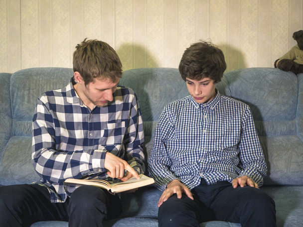 young male teacher and teenager studying at home on the sofa - Photo, Image