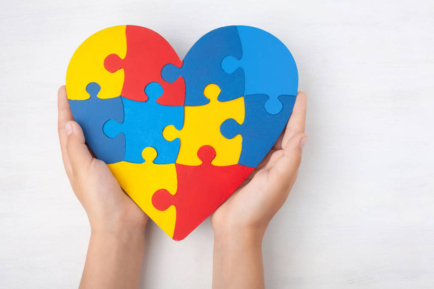 Día Mundial del Autismo, concepto de cuidado de la salud mental con rompecabezas o patrón de rompecabezas en el corazón con manos de niños - Foto, imagen