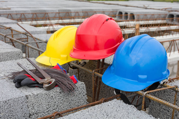 Três capacetes coloridos no local de construção
 - Foto, Imagem