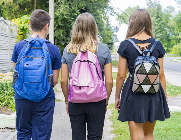 Étudiants adolescents, un garçon et une fille, rentrant à pied de l'école après les cours avec des sacs d'école derrière, vue arrière
 - Photo, image