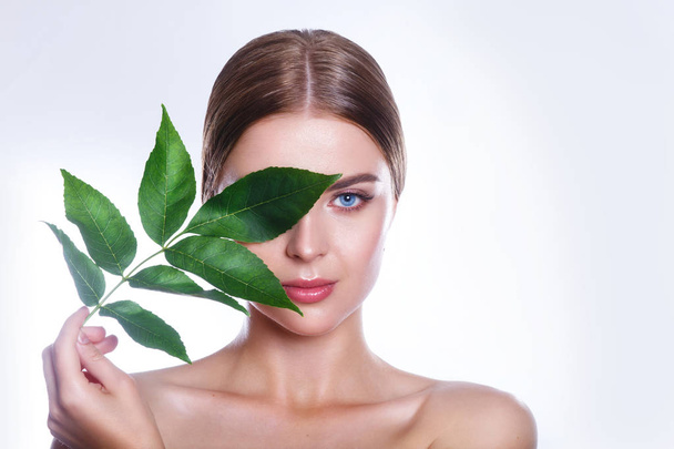Beautiful woman face portrait with green leaf concept for skin care or organic cosmetics. Studio portrait - Photo, image