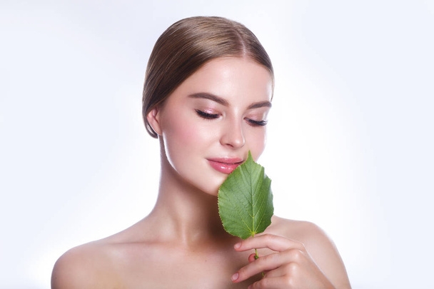 Beautiful woman face portrait with green leaf concept for skin care or organic cosmetics. Studio portrait - Fotó, kép