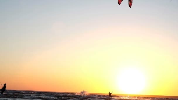 Kitesurfer dělá trik v letu nad vodou proti západu slunce v létě, pomalý pohyb - Záběry, video