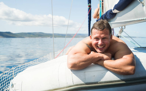 schöner lächelnder Mann entspannt sich beim Sonnenbaden auf seinem Boot - Foto, Bild
