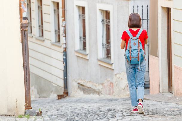 Женщина-туристка с рюкзаком путешествует по романтическим и узким улочкам неузнаваемого европейского города
 - Фото, изображение
