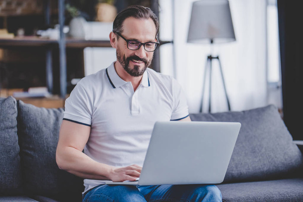 portrait of bearded man wearing glasses working on laptop at home - Zdjęcie, obraz