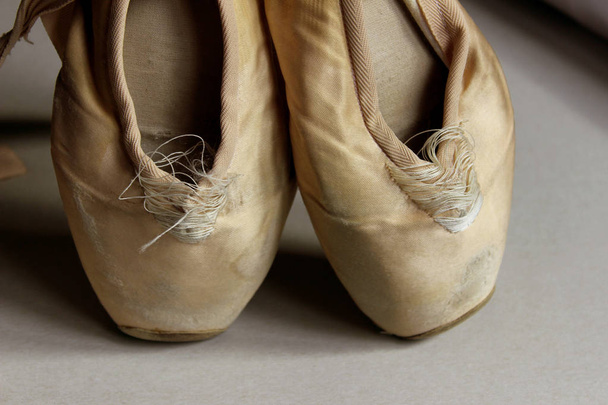 Oříznout záběr staré boty bodu. Baletní obuv, světle hnědé barvy. Pointe boty na podlaze, detail. Abstraktní balet pozadí. - Fotografie, Obrázek