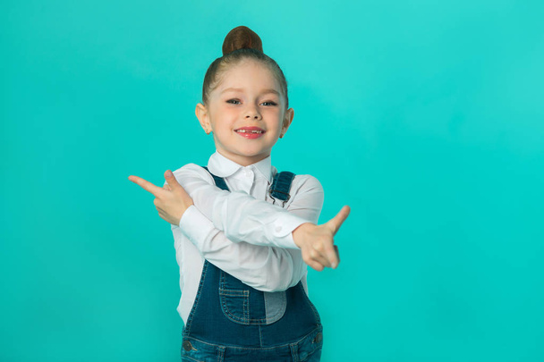 beautiful little happy girl in jeans and a white shirt on a blue background - Foto, immagini