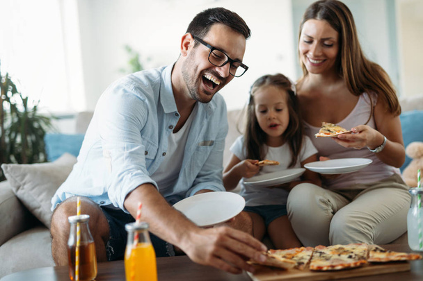 Muotokuva onnellinen perhe jakaa pizzaa yhdessä kotona
 - Valokuva, kuva