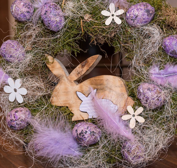 διακοσμητικό Πασχαλινό στεφάνι με πολύχρωμα αυγά και ξύλινα κουνέλι - Φωτογραφία, εικόνα