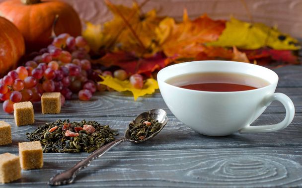 Cup of tea. Dry tea leaf.  Tea with spicy additives. Sugar. Autumn background. White cup. Close up. Selective focus. - Foto, imagen