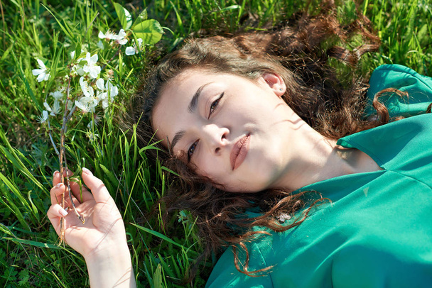beautiful girl lying on the grass at sunny day, face closeup, summer forest, bright landscape with shadows - Fotó, kép
