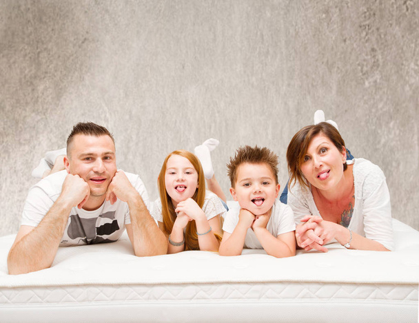 Семья кузнецов развлекается, лежа на кровати
 - Фото, изображение