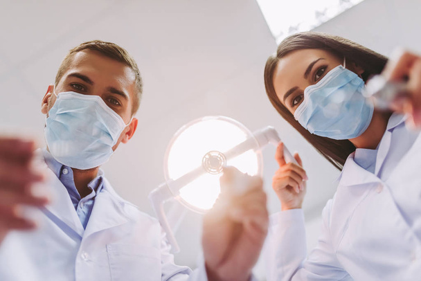 close up portrait of female dentist and male assistant holding dental tools in modern dental clinic - Foto, afbeelding