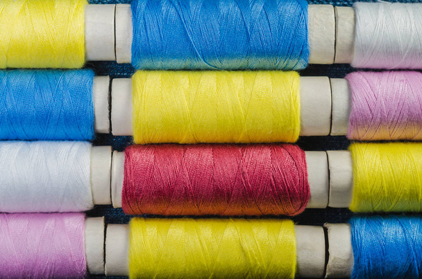 Катушки разноцветных нитей, расположенные рядами
 - Фото, изображение