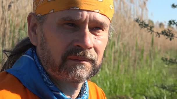Porträt des reifen Menschen in der Natur. Bärtiger Reisender mit Kopftuch lächelt - Filmmaterial, Video