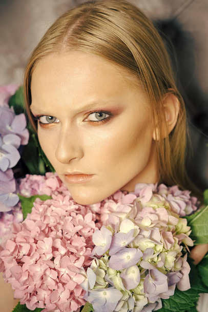 Hydrangeas in the beauty salon. Young beauty woman face with blond hair and hydrangea - Foto, afbeelding