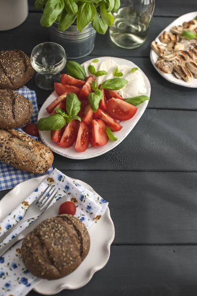 Salad with caprese, fresh basil and grain bread on a black background. Copy space, flat lay - Photo, Image