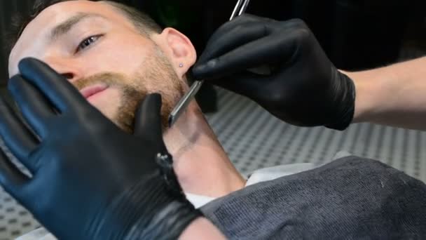 Beard cut with straight razor shave. Close up of shaving beard in barber shop. Male beard style. Barber shaving hipster man face - Footage, Video