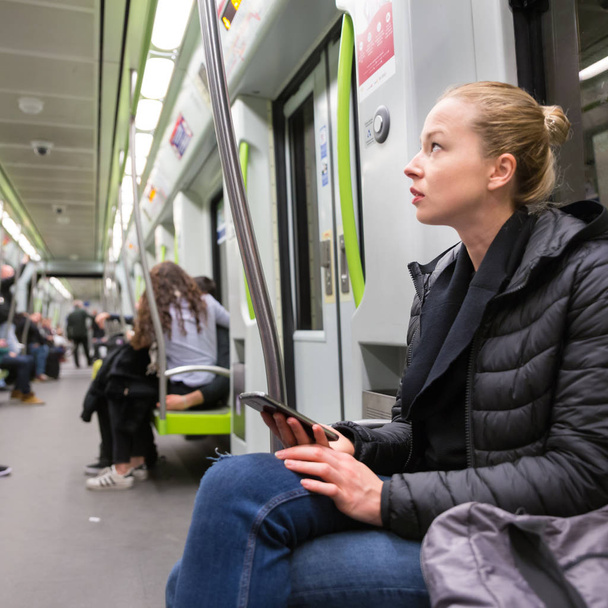 Chica joven con teléfono móvil que viaja en metro
. - Foto, imagen