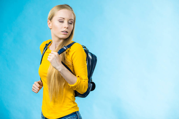 Blonde teenage girl going to school or college wearing stylish backpack. Outfit trendy accessories. On blue - Фото, изображение