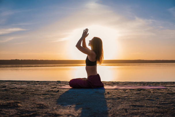 Sziluettjét jóga nő a tengerparton naplementekor. - Fotó, kép
