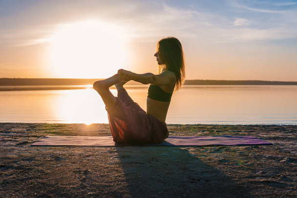 Silueta mujer yoga en la playa al atardecer
. - Foto, Imagen