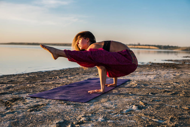 Mujer del yoga en la playa al atardecer
. - Foto, Imagen