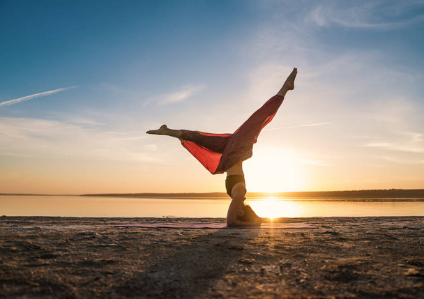 Silhouette yoga femme sur la plage au coucher du soleil
. - Photo, image