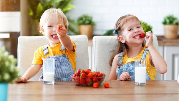 Happy children girl and boy brother and sister eating strawberries with mil - Φωτογραφία, εικόνα