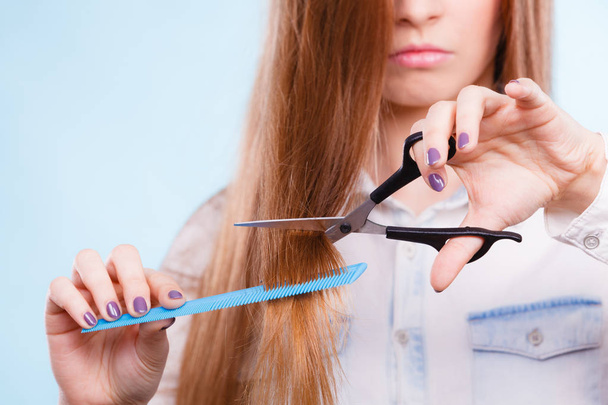 Change of look, new image. Young girl presents comb and scissors. Female stylist preparing equipment to work cut long straight healthy hair. - 写真・画像