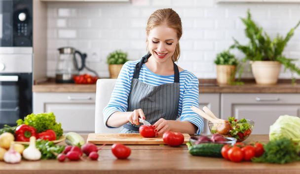 счастливая женщина готовит овощной салат на кухне
 - Фото, изображение