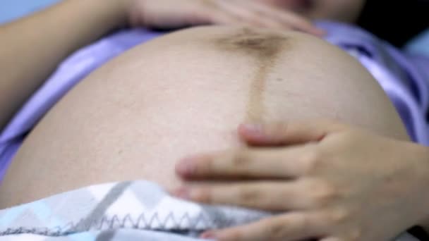 Chiudi i movimenti del bambino durante la gravidanza. Donna incinta sdraiata sul letto e toccando la sua grande pancia nuda. Bambino in movimento nel grembo della madre
. - Filmati, video