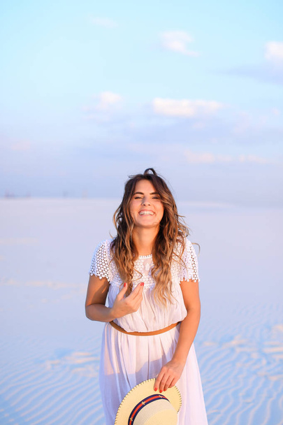 Happy female person keeping hat, wearing white dress standing on - Fotoğraf, Görsel