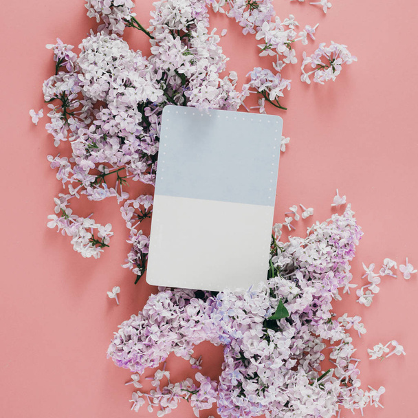 Flat lay card with lilac flowers on pink background, top view - Фото, изображение