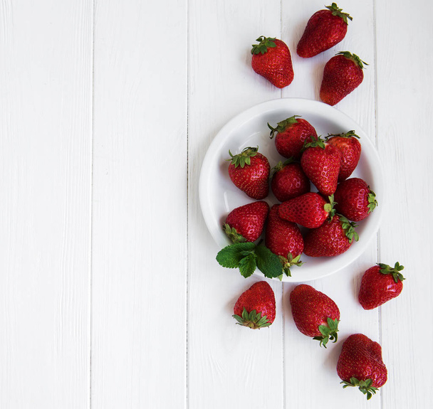 Assiette avec des fraises fraîches sur une table en bois blanc
 - Photo, image