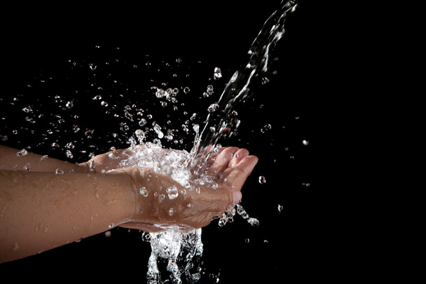 hand and pouring water on black background - Foto, immagini